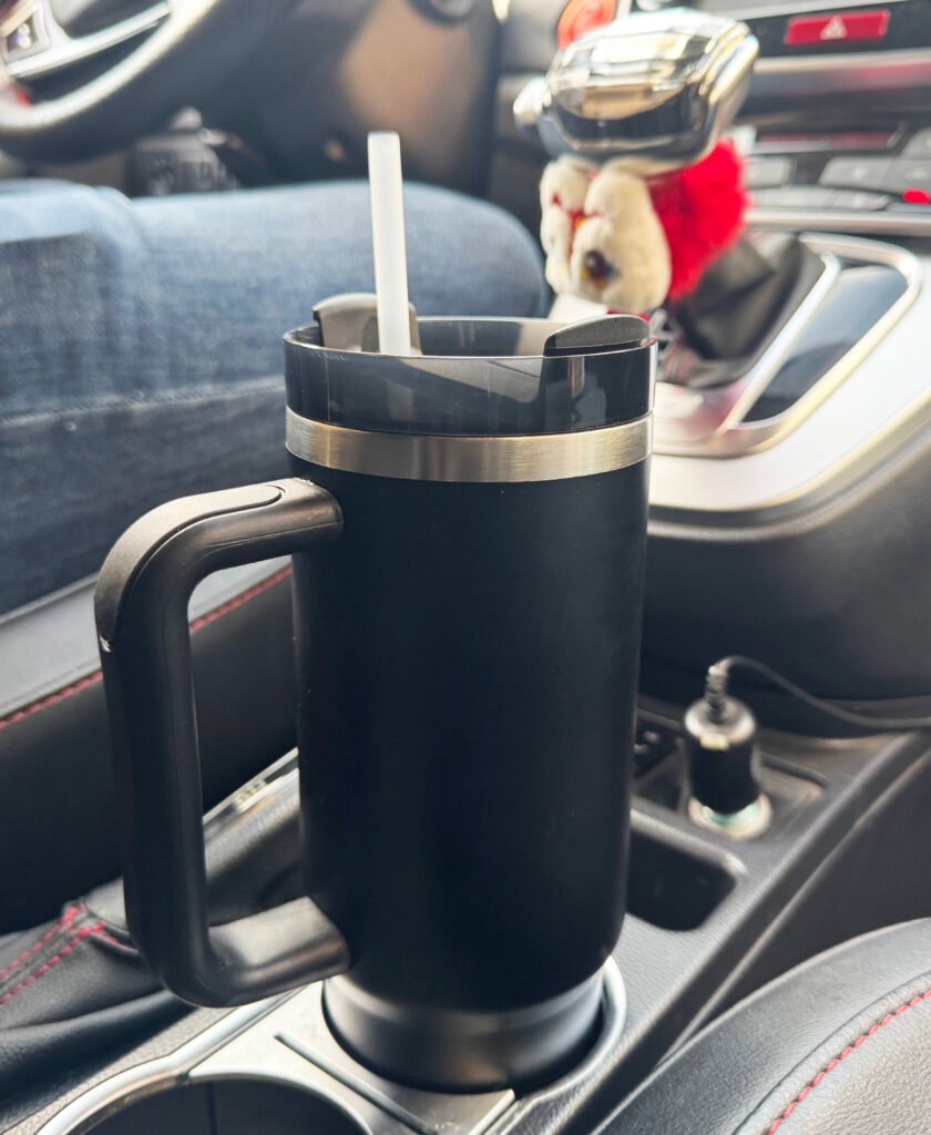 A stainless steel handle thermos cup placed inside a car, ideal for travel convenience.