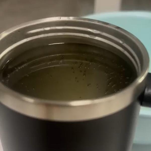 Boiling water being poured into a handle thermos cup for heat retention testing.