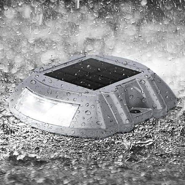 Solar road stud light glowing in the rain, ensuring safety.