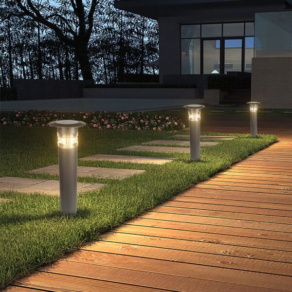 Three solar garden lights glowing in a row on a grassy field