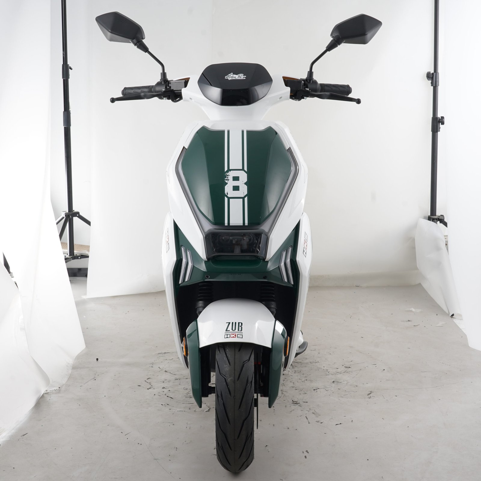 Front view of a white and green electric motorcycle showing the front lighting, handlebars and front tire