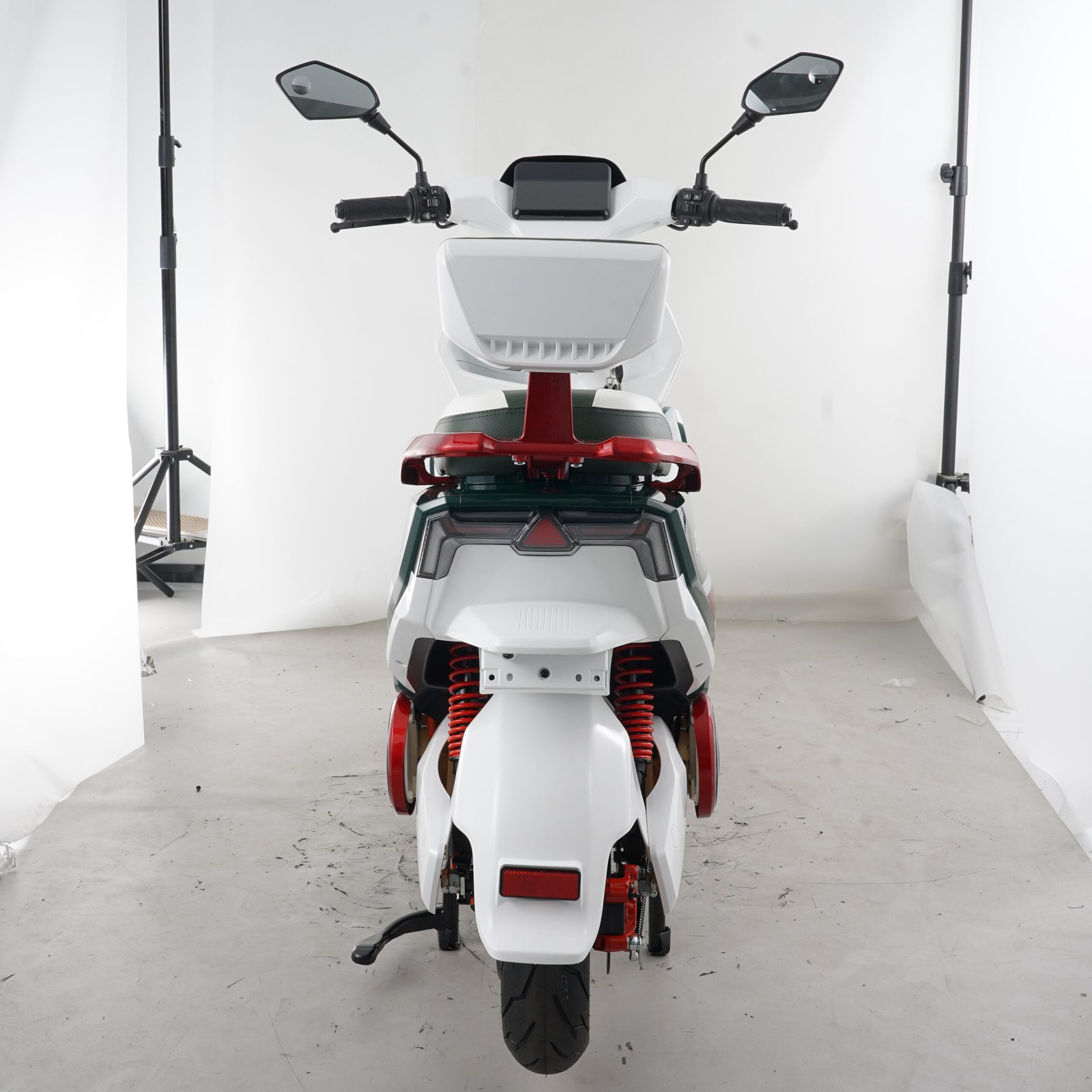 Rear view of a white and green electric motorcycle showing the passenger backrest, taillight, rear suspension and wheel