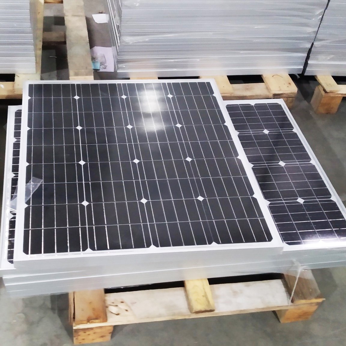 Different sizes of small monocrystalline solar panels arranged on pallets for wattage comparison